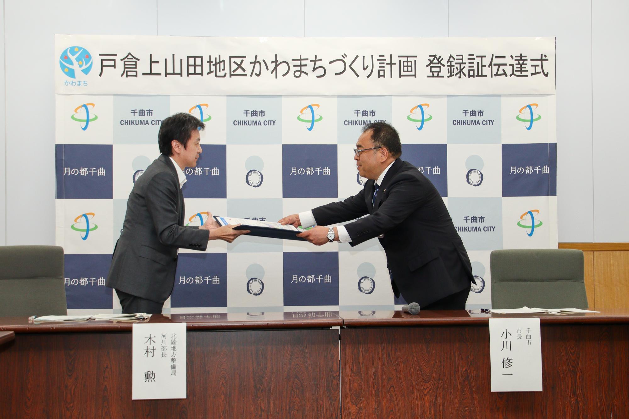 国土交通省北陸地方整備局の木村勲河川部長(左)からかわまちづくり計画登録証を伝達される小川修一市長(右)