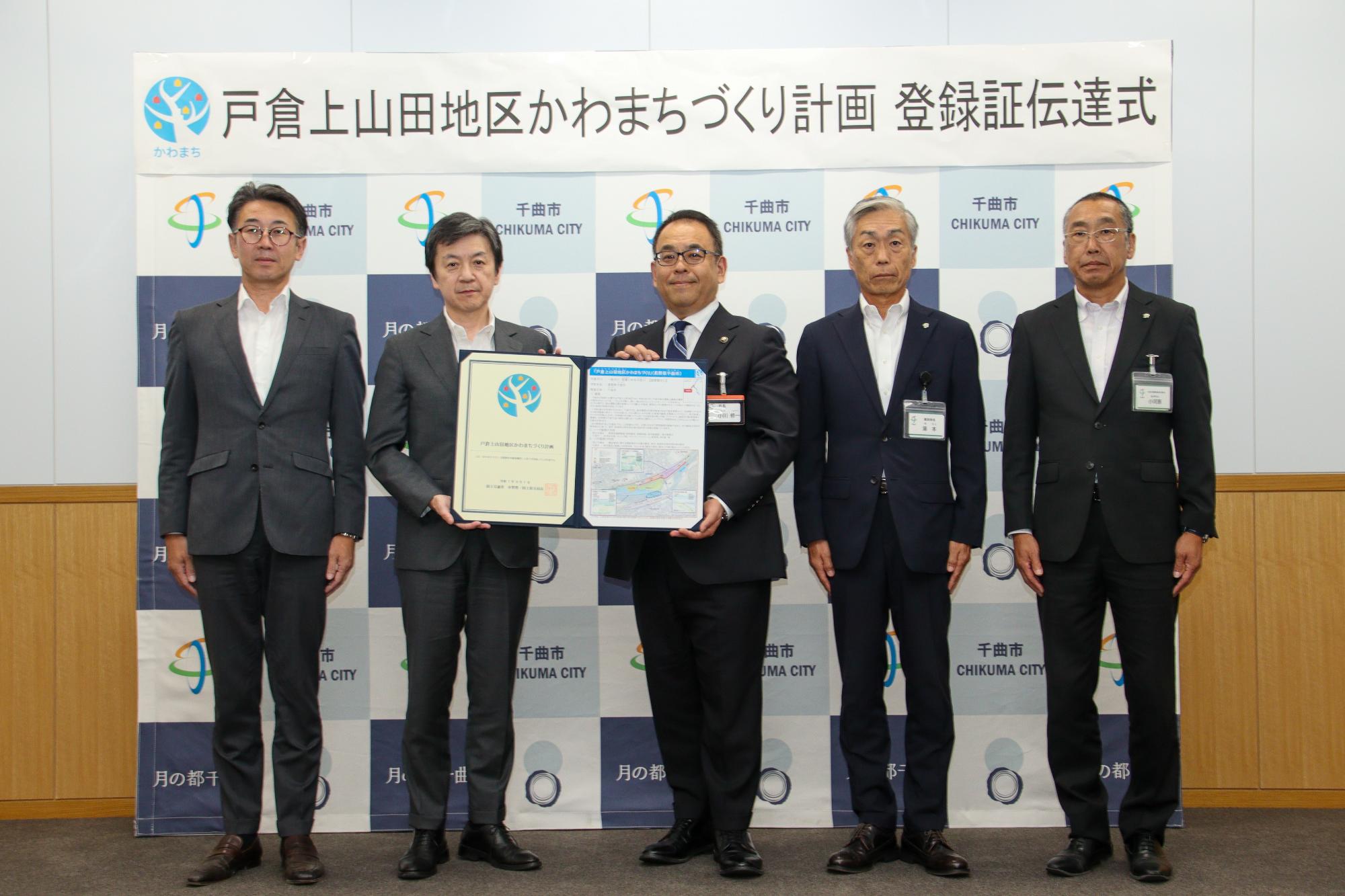 かわまちづくり計画登録証の伝達を受け記念撮影。右から小河原公民共創担当部長、湯本建設部長、小川市長、国土交通省北陸地方整備局木村河川部長、千曲川河川事務所浅見事務所長