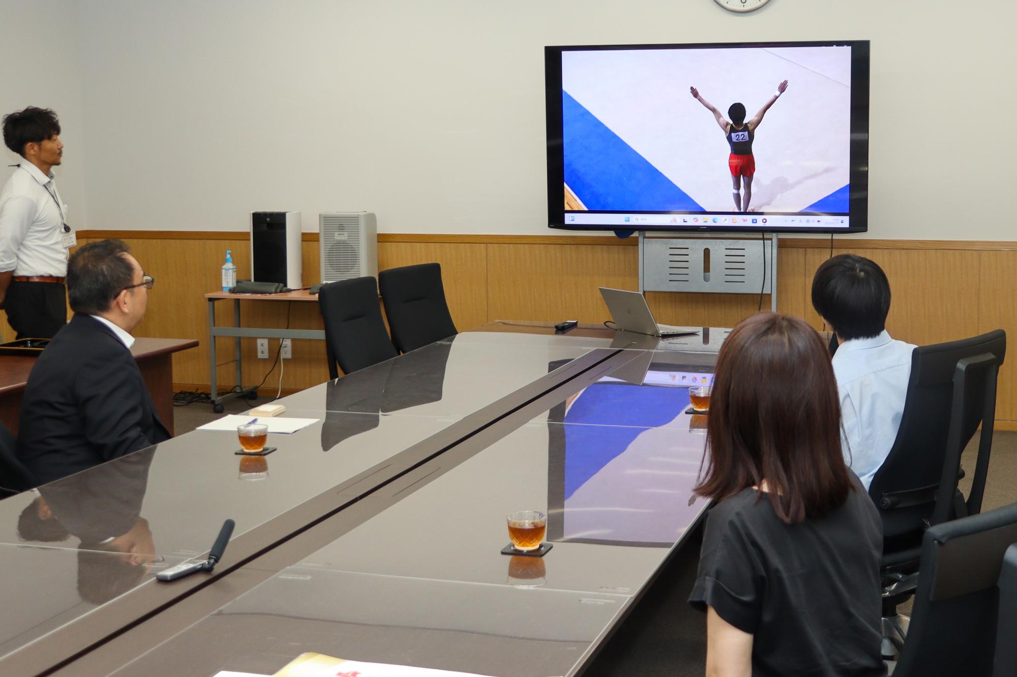 小椋さんの県大会での演技の映像を見ている小川市長(左)と小椋さん(右)