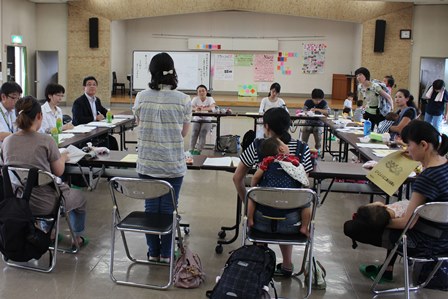 机を四角に並べて市長と意見交換をしているママさんたちの姿を映した会場の全景写真