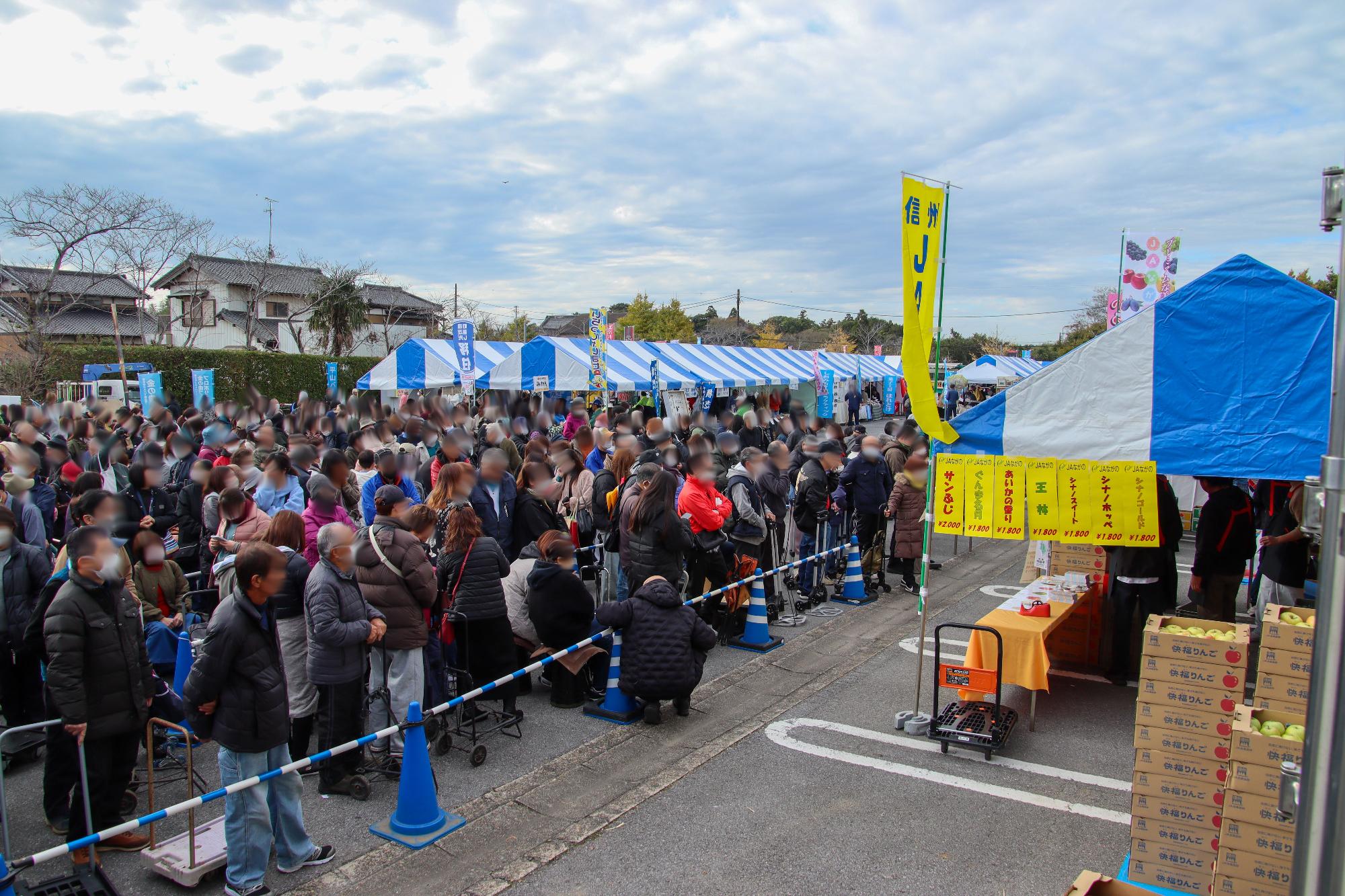 千葉県横芝光町産業まつりにりんご販売で出店している千曲市ブースの前に大勢のお客さんが並んでいる様子