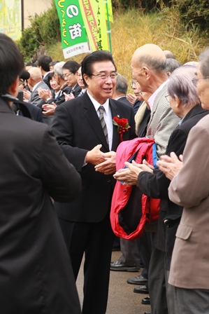 沿道に集まった支持者と握手をしながら歩く市長の写真