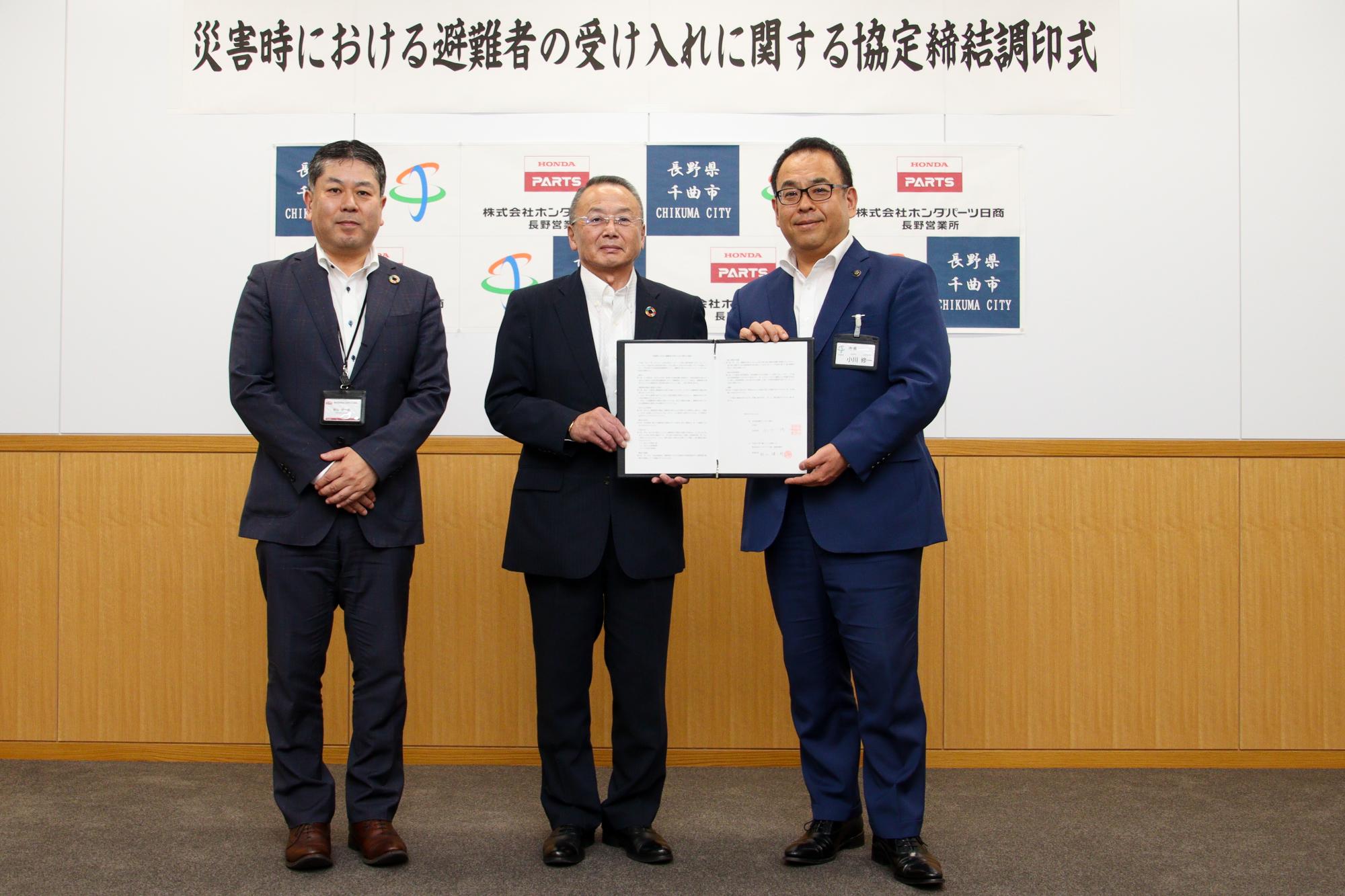 協定書を持ち記念撮影をする郡司代表取締役社長(中央)と小川市長(右)、秋山長野営業所長(左)