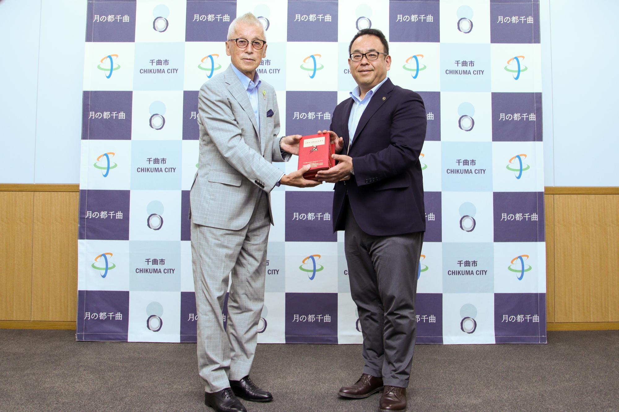 「ハチドリのひとしずく」書籍を二人で持って記念撮影する小出会長と小川市長