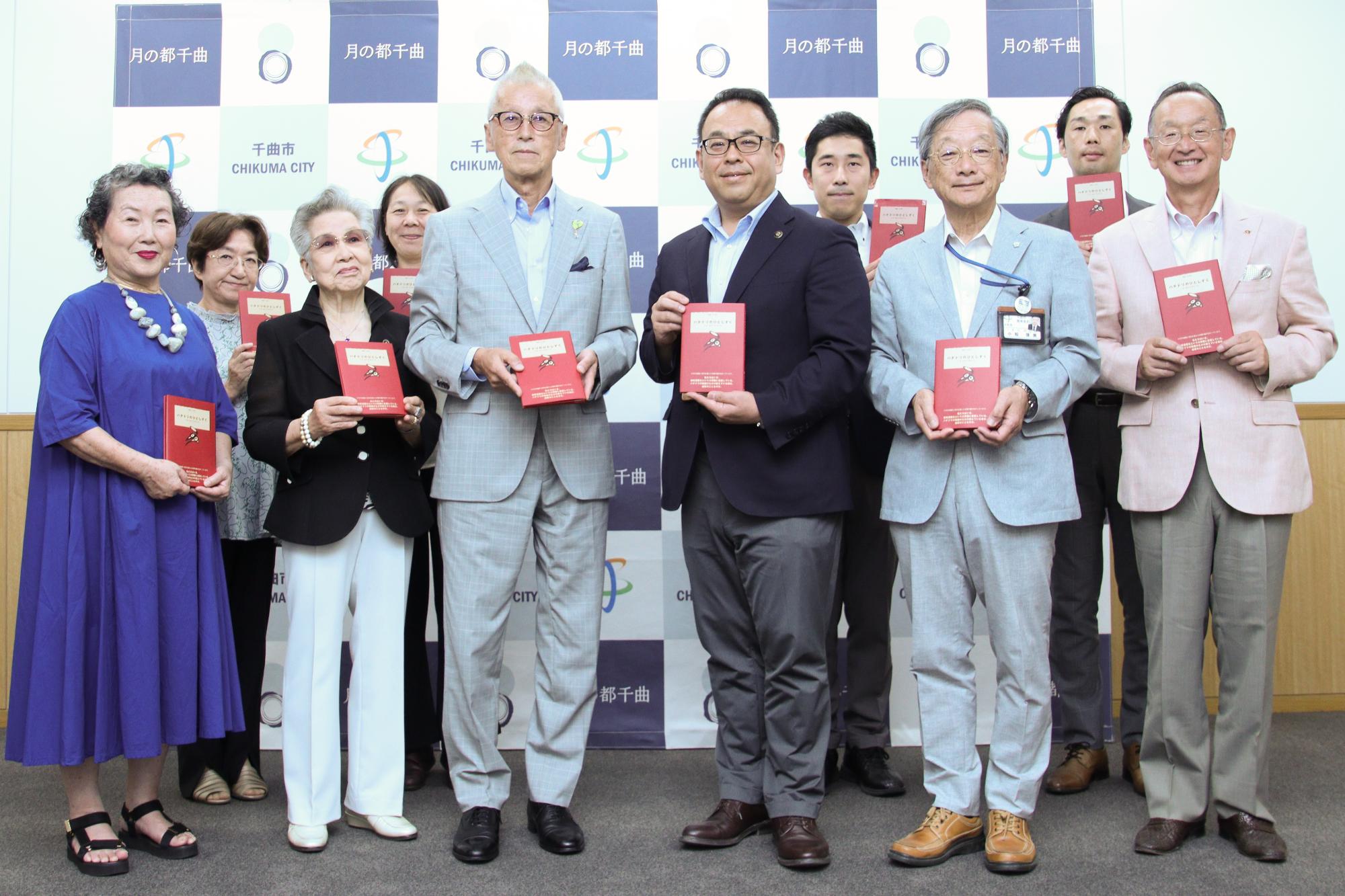 書籍「ハチドリのひとしずく」を手にもって記念撮影する小川市長と長野ハチドリのひとしずくの会の皆さん