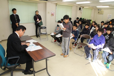 会議室で市長に意見を発表する小学生の男の子とそれを聞く市長の写真