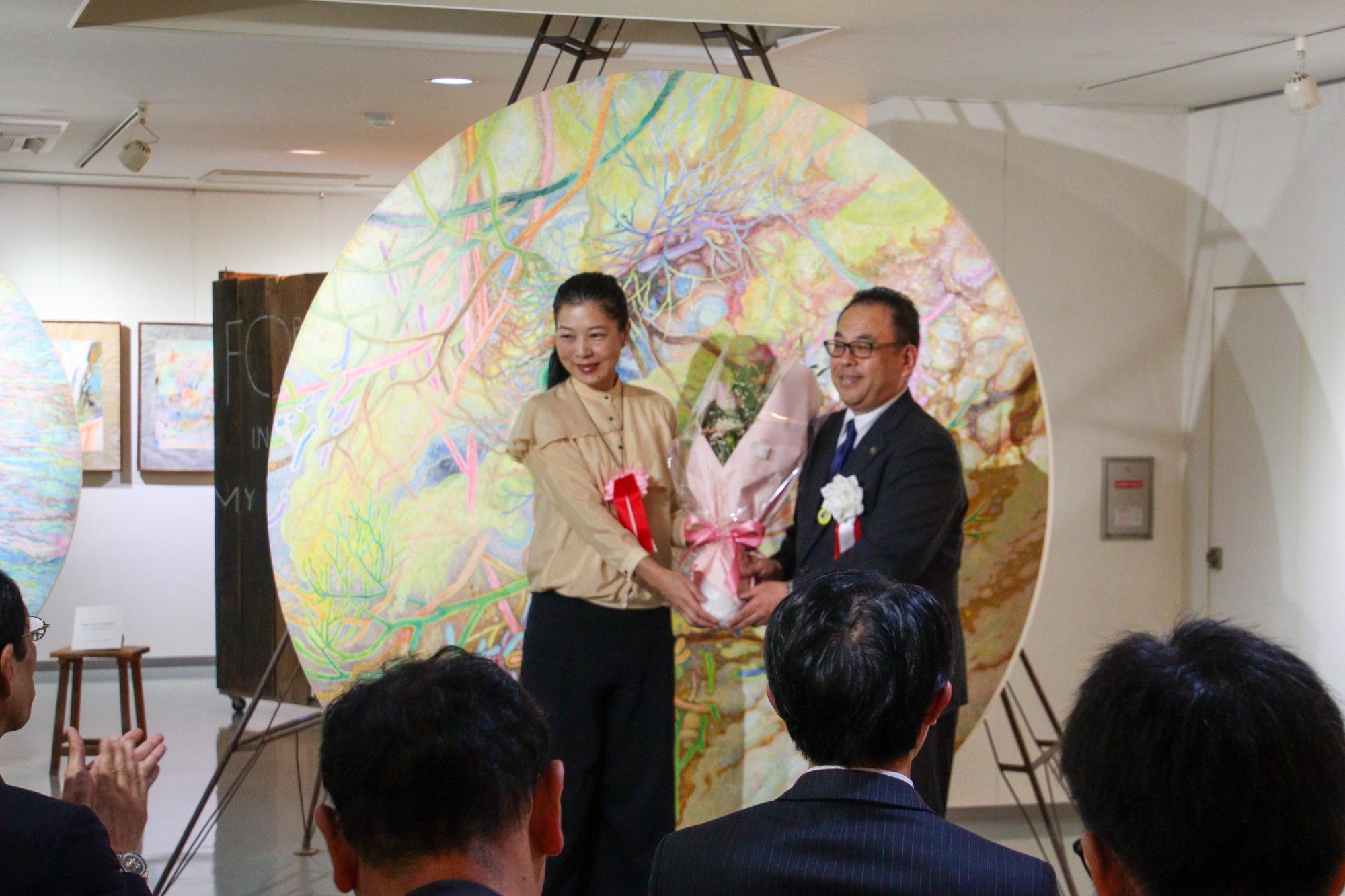白井ゆみ枝さん(左)に花束を贈呈する小川市長(右)