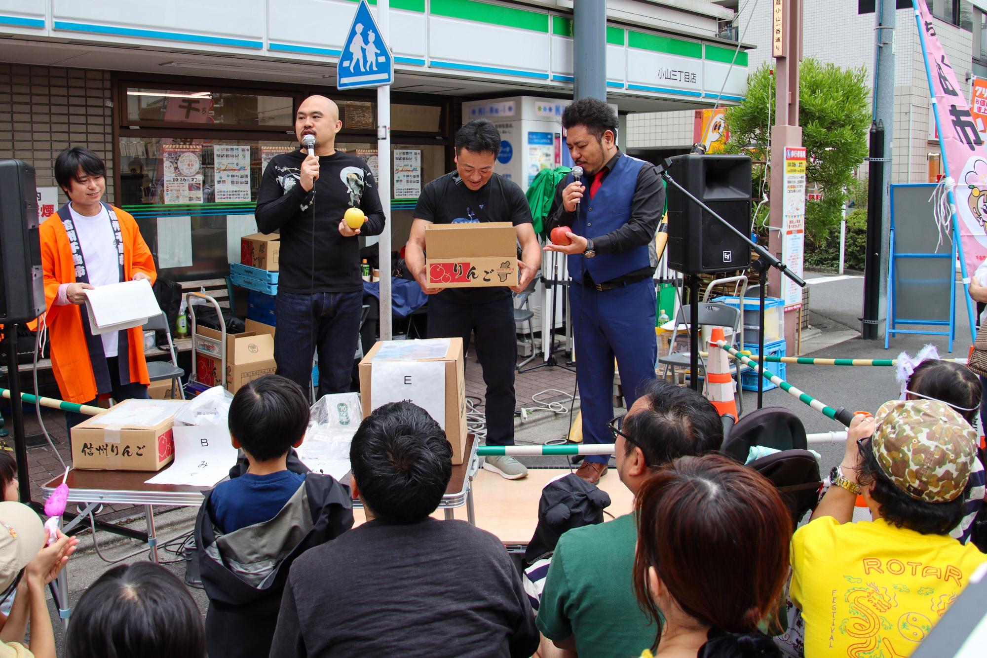 ムサコマルシェでイベントを行なう鬼越トマホークの2人(左右)と事業者(中央)の皆さんも参加したクイズ大会