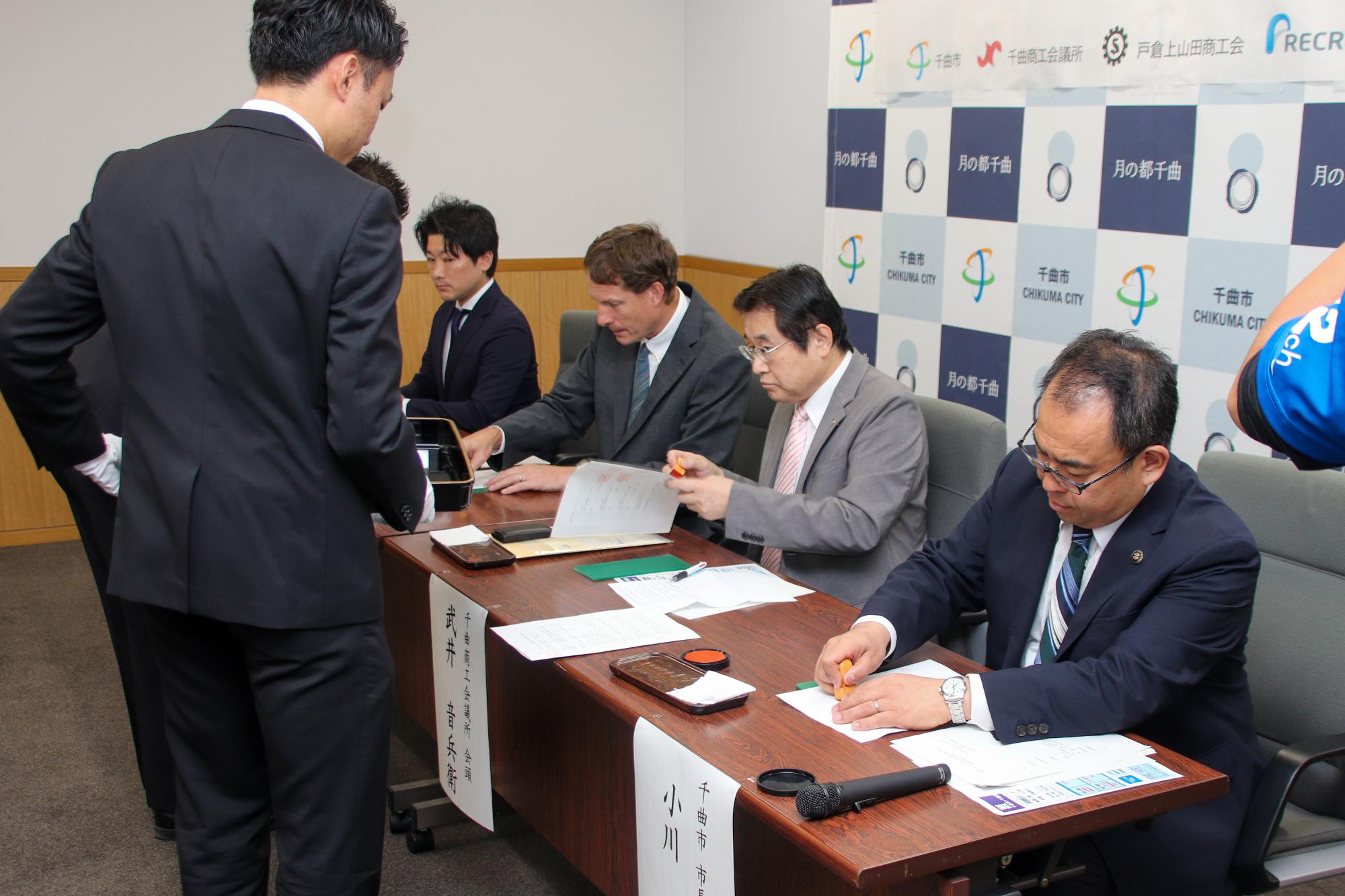 地域活性化に向けた地域定着と雇用促進に関する連携協定に捺印する様子