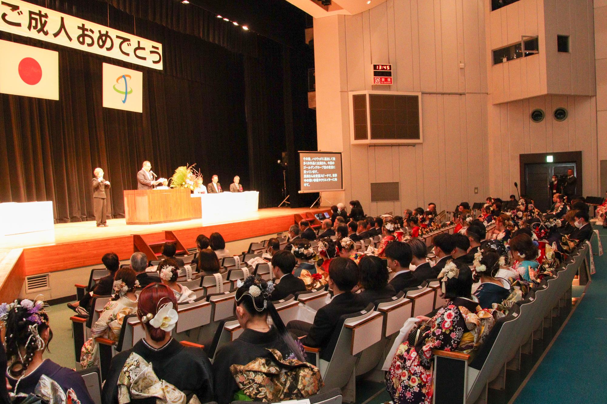 成人式の式典で、新成人の前で市長が祝辞を述べている写真