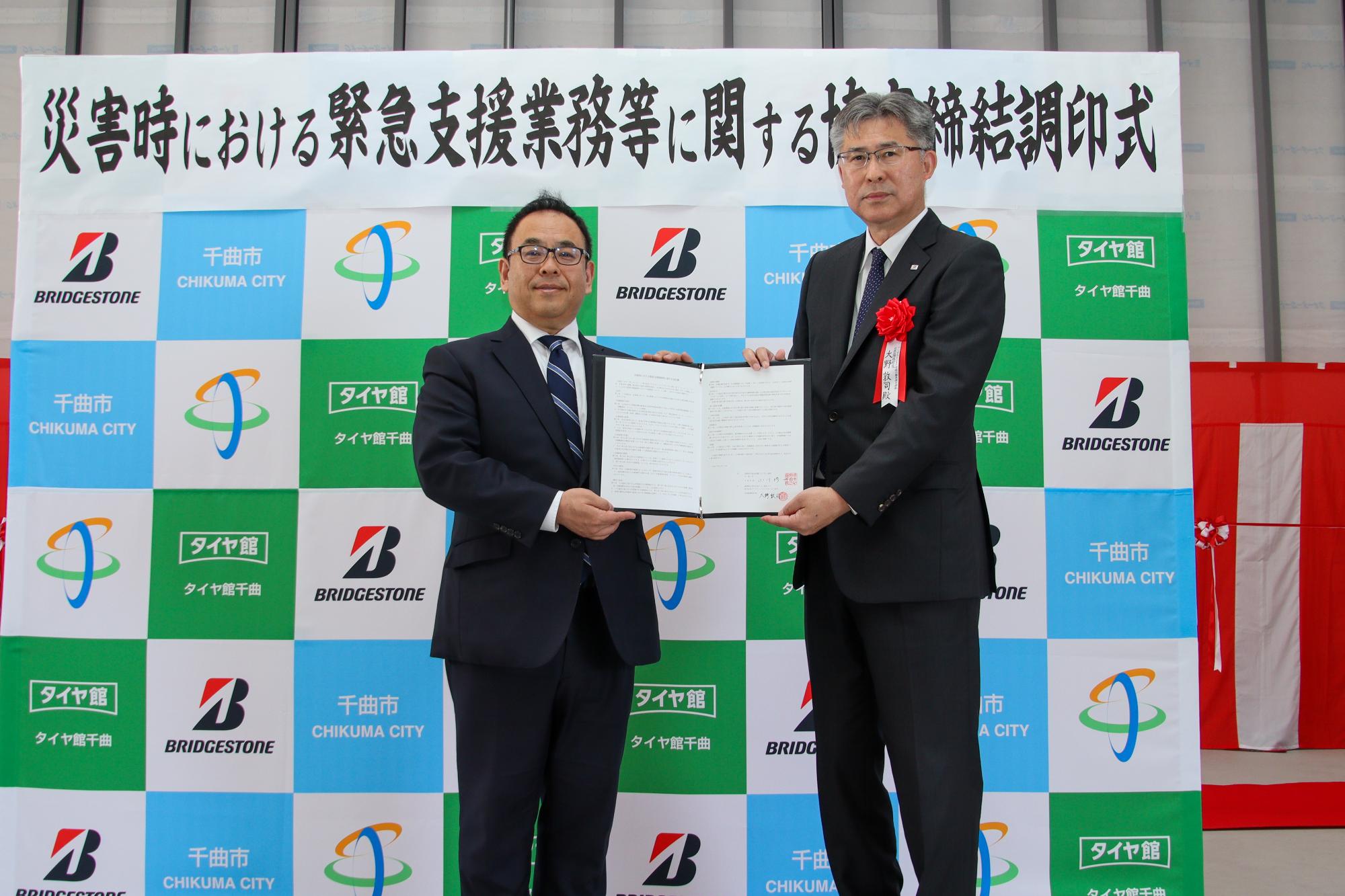 調印した協定書を披露する小川市長(左)と大野代表取締役社長(右)