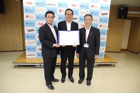 調印式の会場で協定書を広げて記念撮影をする市長と社長らの写真