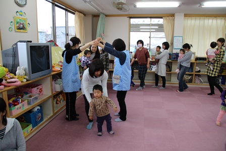 先生たちが作った手のアーチをお母さんと子供がくぐっている写真