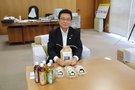 市長がお米のパッケージを手に笑顔でカメラのほうを向いている写真