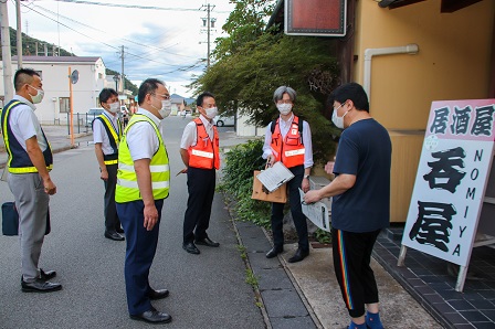 看板が出ている飲み屋の前で集まっている男性スタッフたちの写真