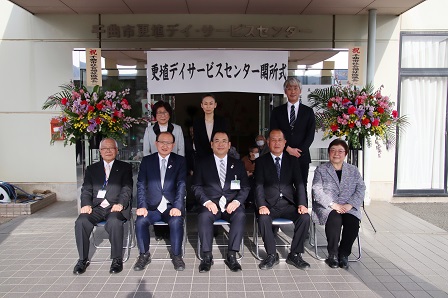 デイサービスセンターの入口で並んで記念撮影をしている人達の写真