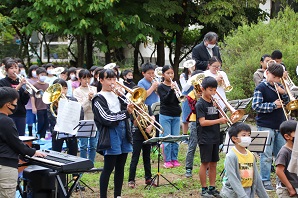 トロンペットやキーボードなどの楽器を屋外で演奏する子供たちの写真