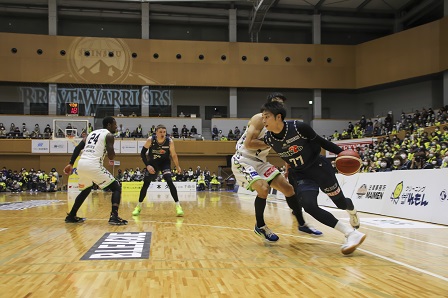 観客たちが見守る中、バスケットボールの試合が行われている写真