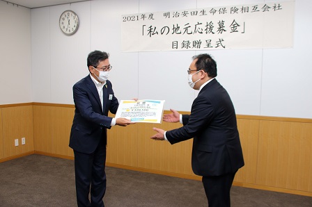 明治安田生命保険相互会社長野支社の石田上田営業部長が小川市長に目録を手渡す様子