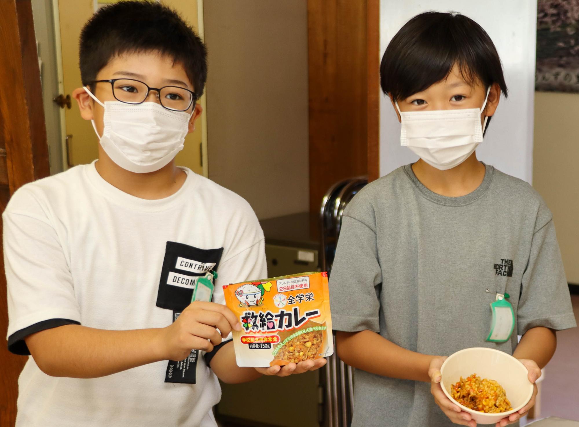 柳澤さんと東海さんが救給カレーを持って、カメラに紹介