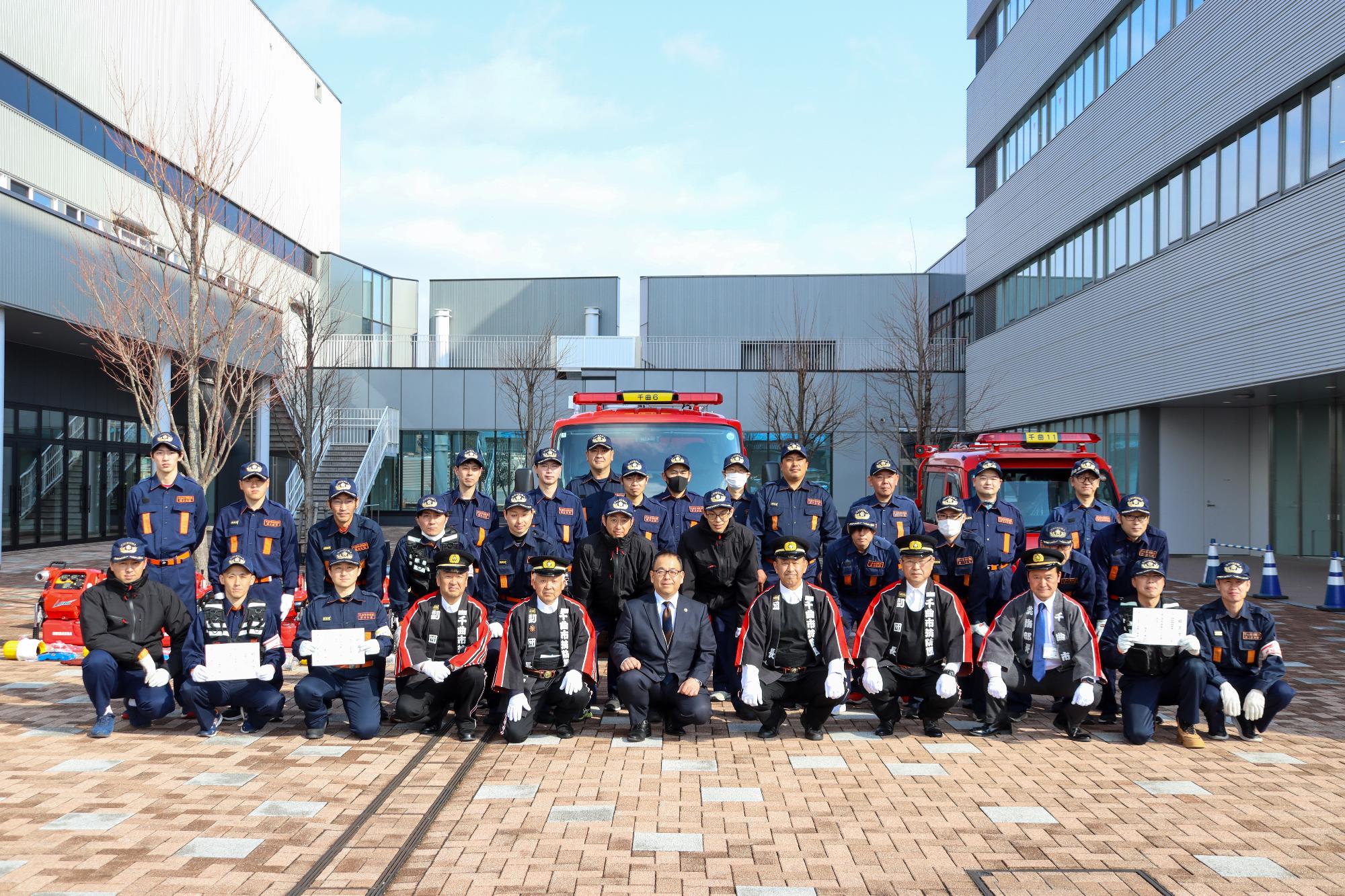 出席者32人が配置された車両やポンプを前に記念撮影している様子