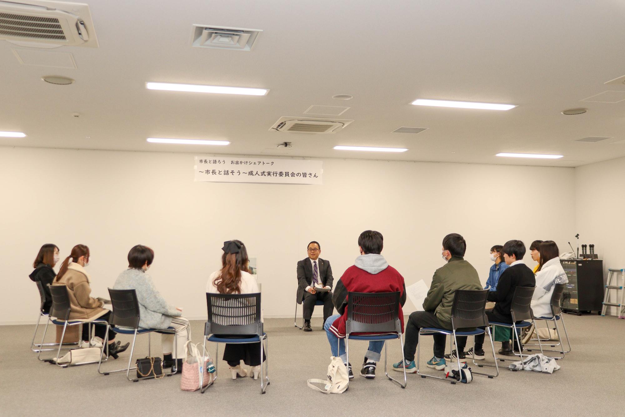 市長と成人式実行委員10人が椅子を円状に並べて懇談する様子を後方から撮影