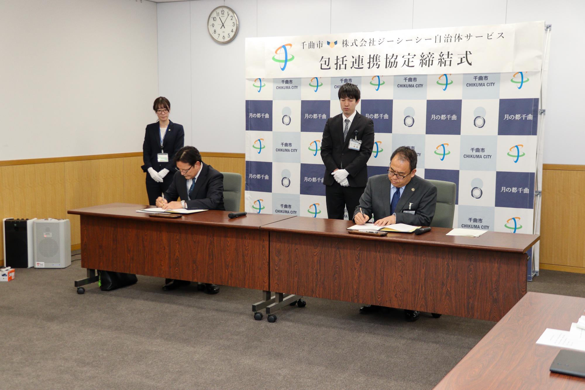 協定書に署名する岡田社長と小川市長
