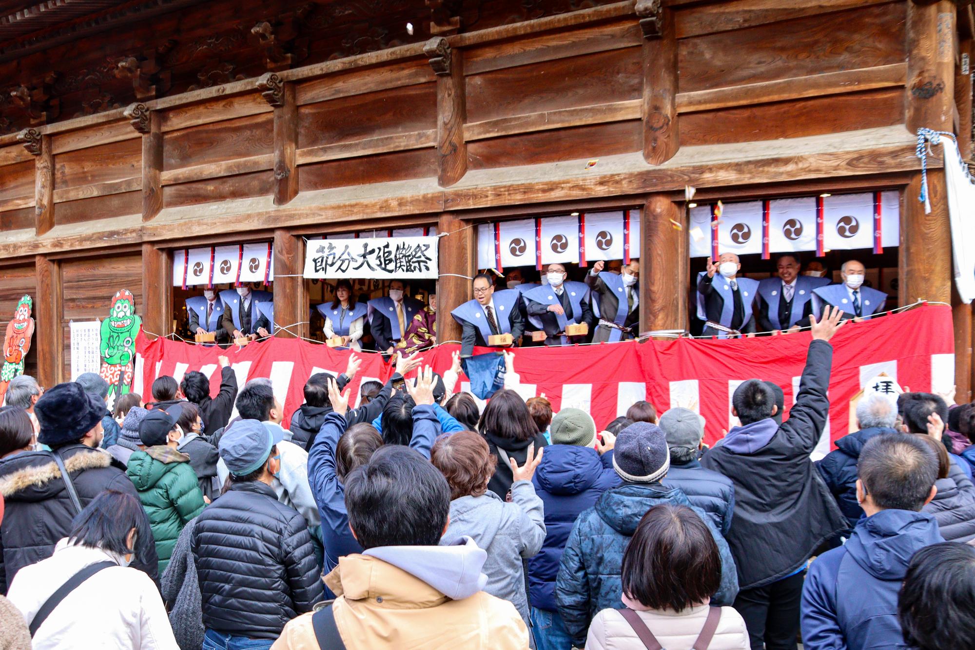 拝殿から豆をまく区長ら約15人と豆を受け取ろうとする人々
