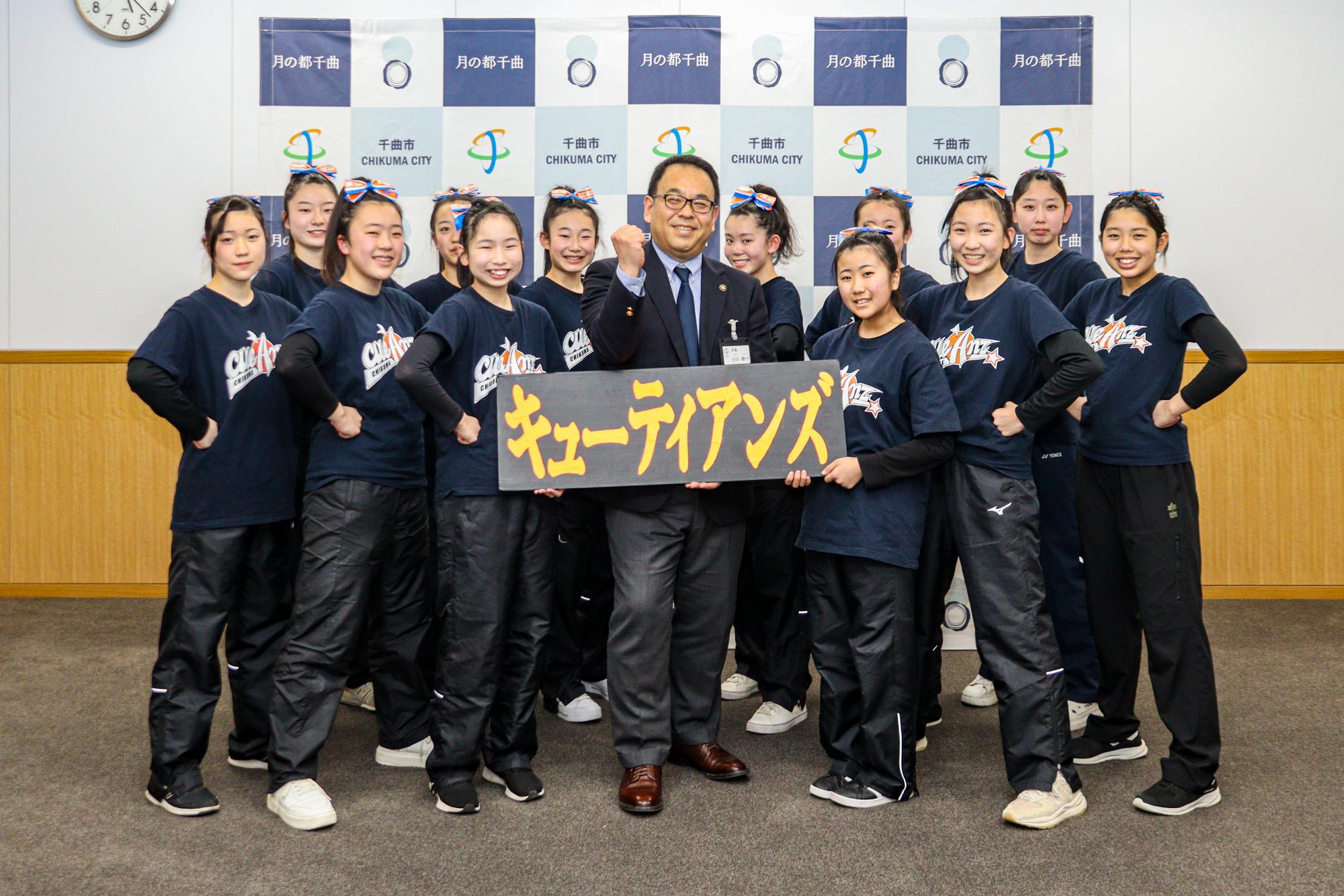 キューティアンズの12人と小川市長がポーズを決めながら記念撮影