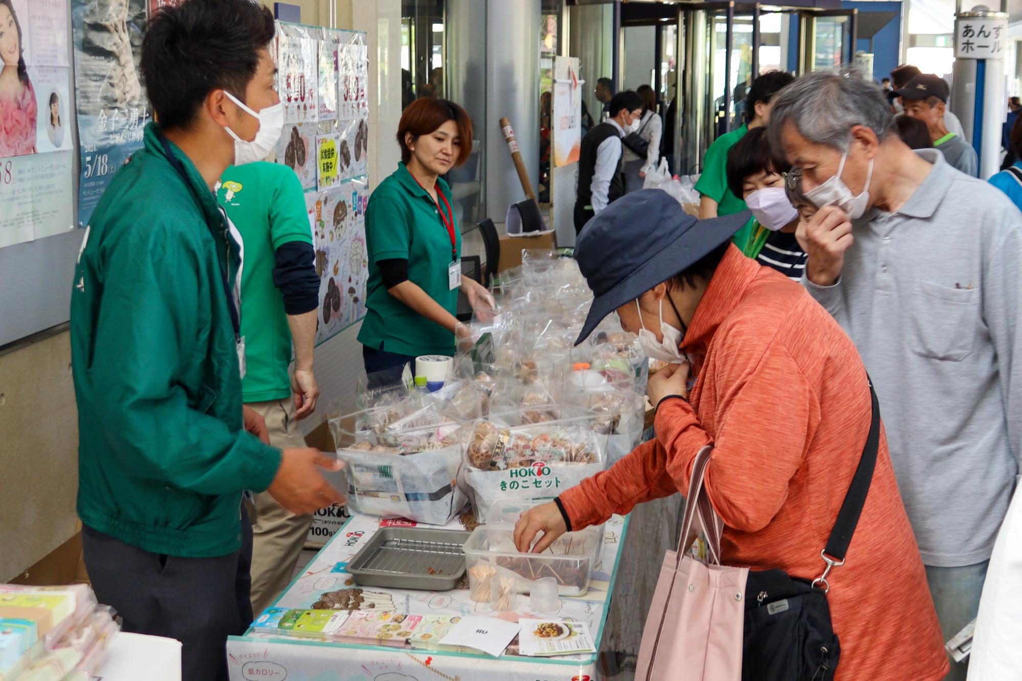 きのこ販売のブースできのこ料理を試食する女性