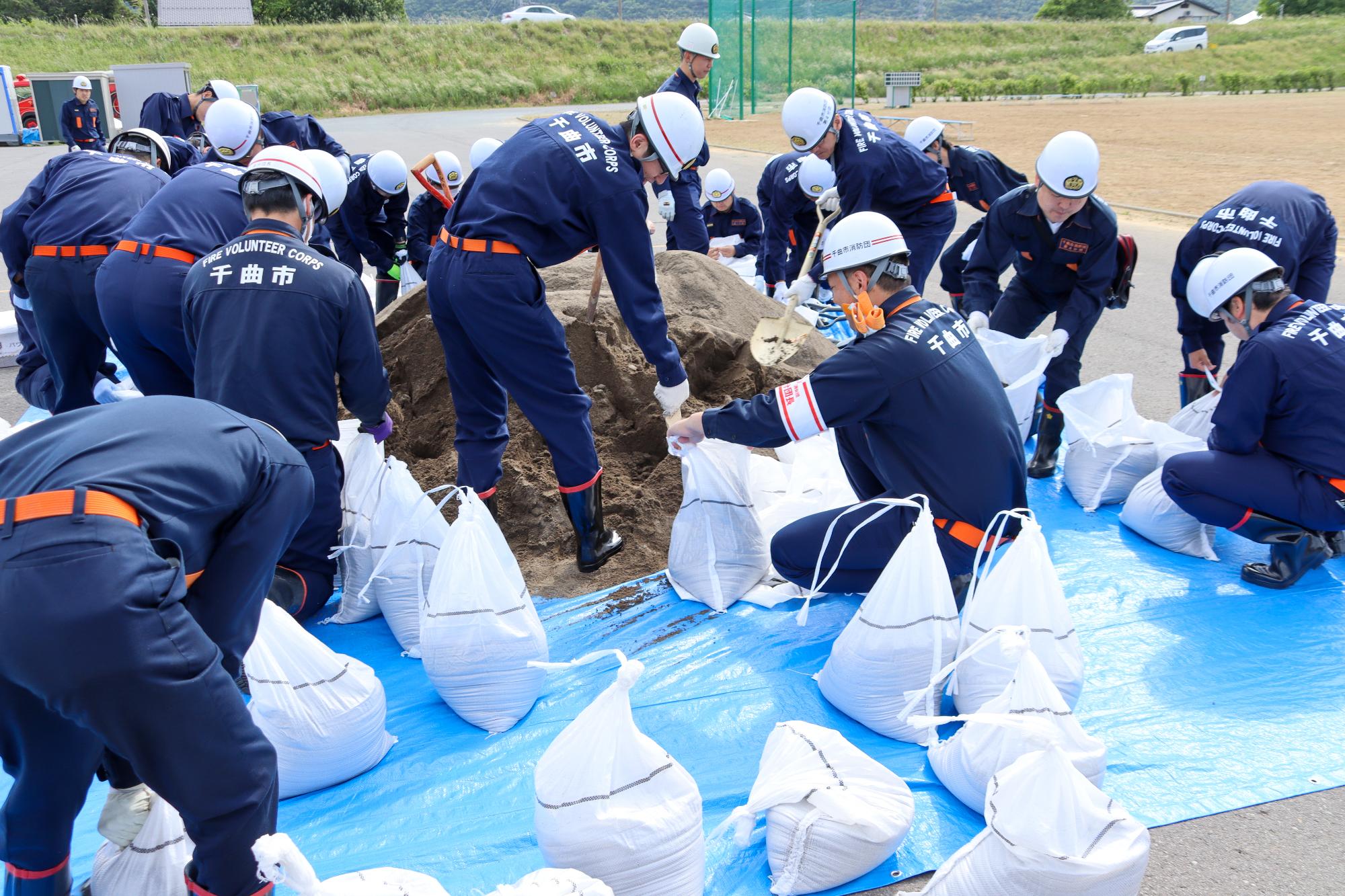 消防団員20~30人が土のう袋に砂を入れ、土のう作成している様子