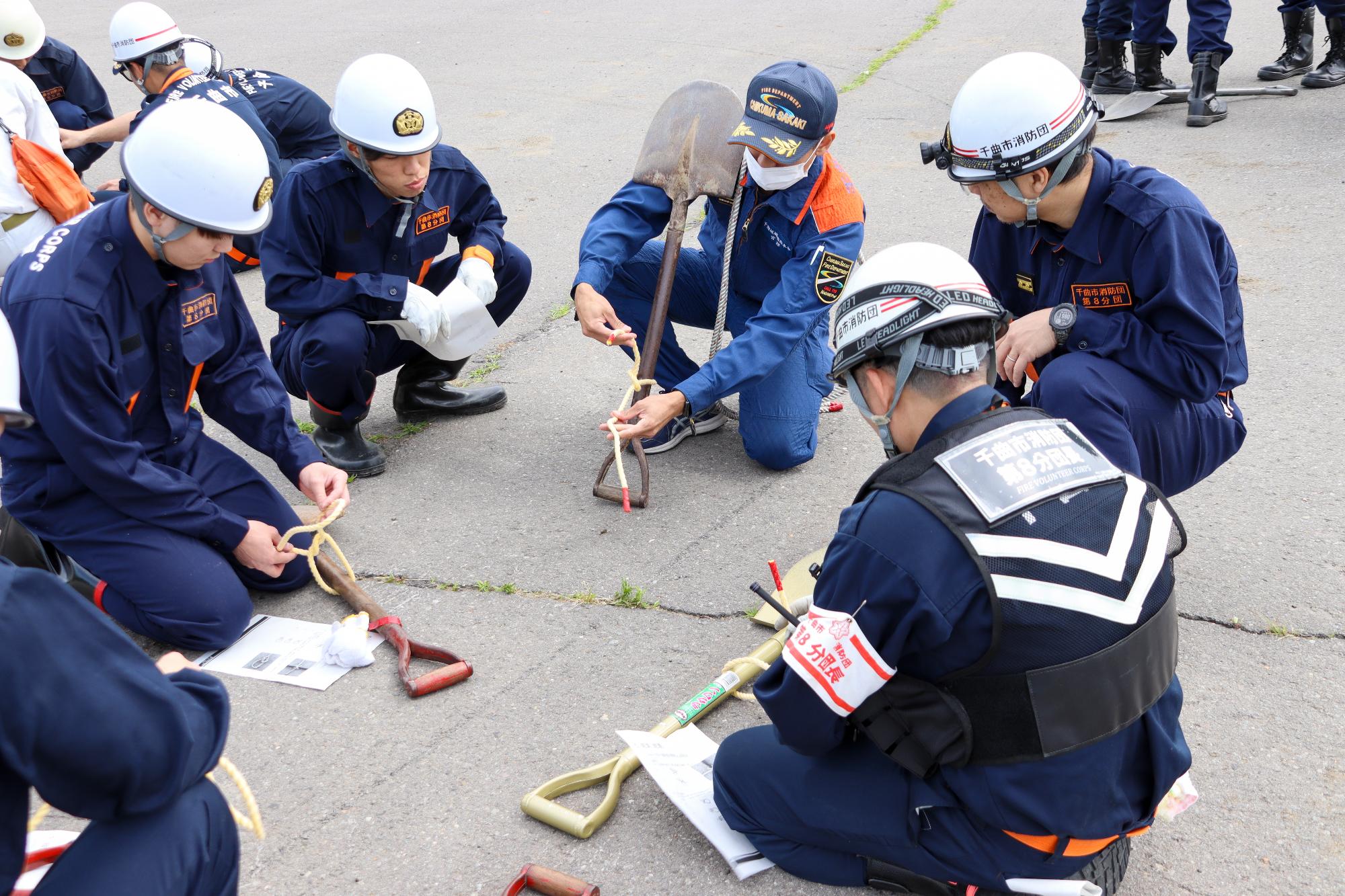 消防本部職員にロープの結び方の指導を受ける消防団員4人