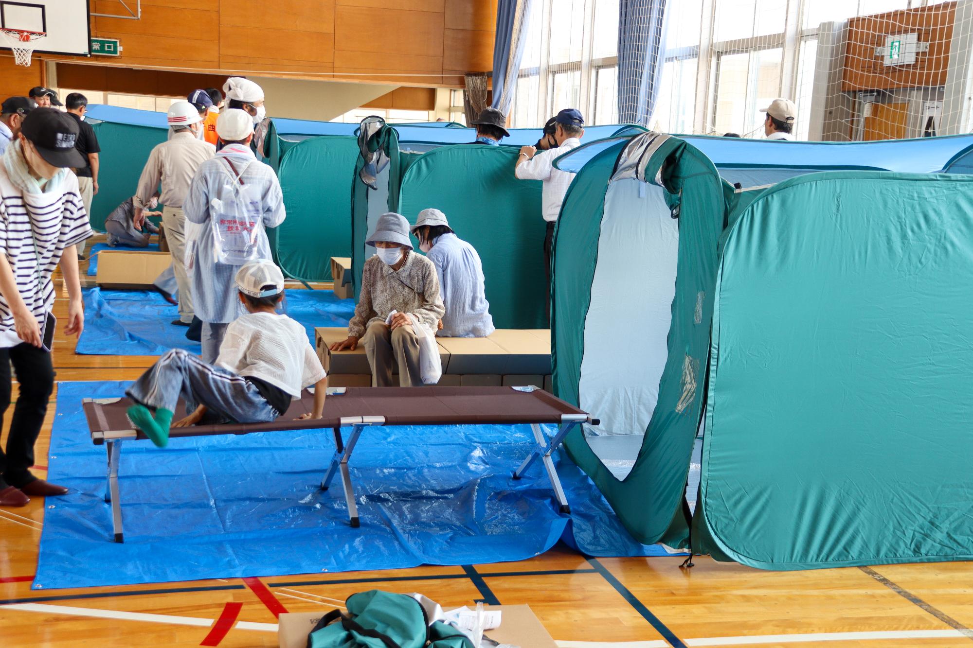 避難所設営訓練で設置が完了したパーティションや段ボールベッドに触れる参加者