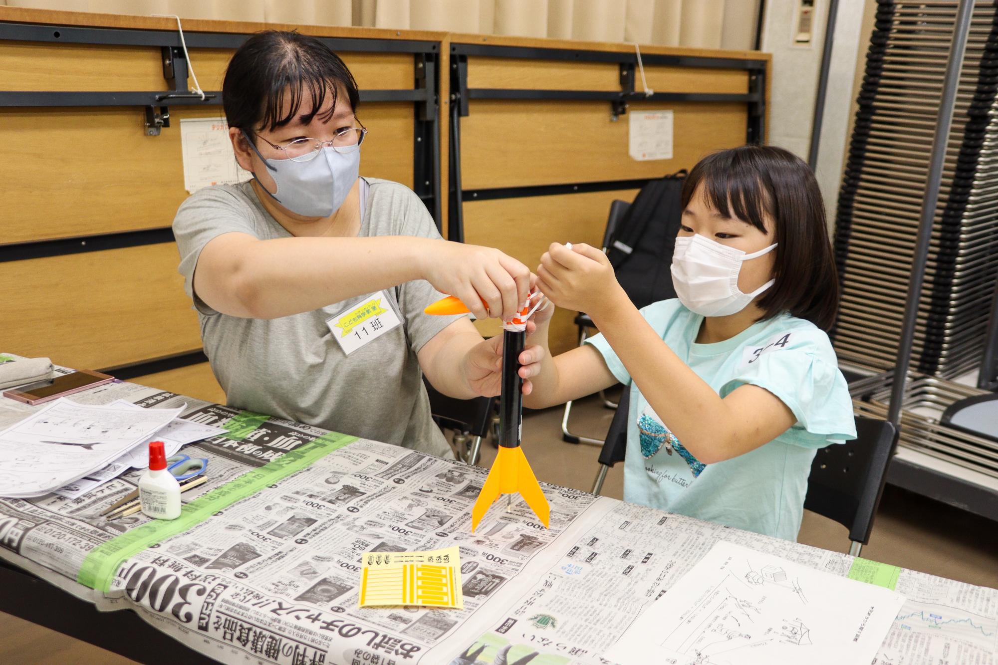 ロケットにパラシュートを入れる母娘
