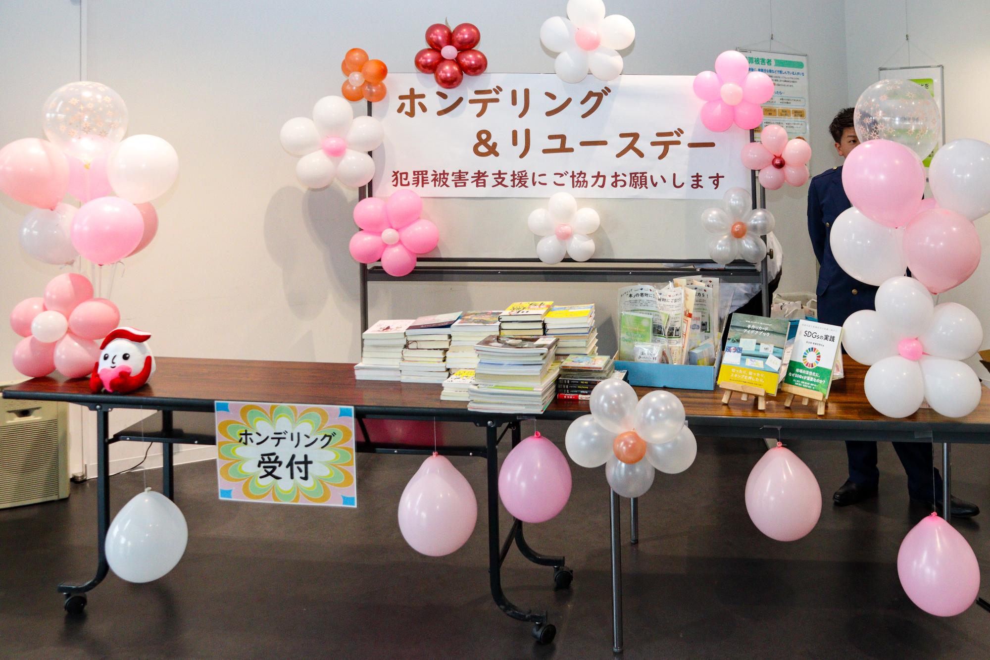 ホンデリングデーの受付の様子。寄付された本が50冊くらい積まれている。また風船で作られた花が飾り付けられている。