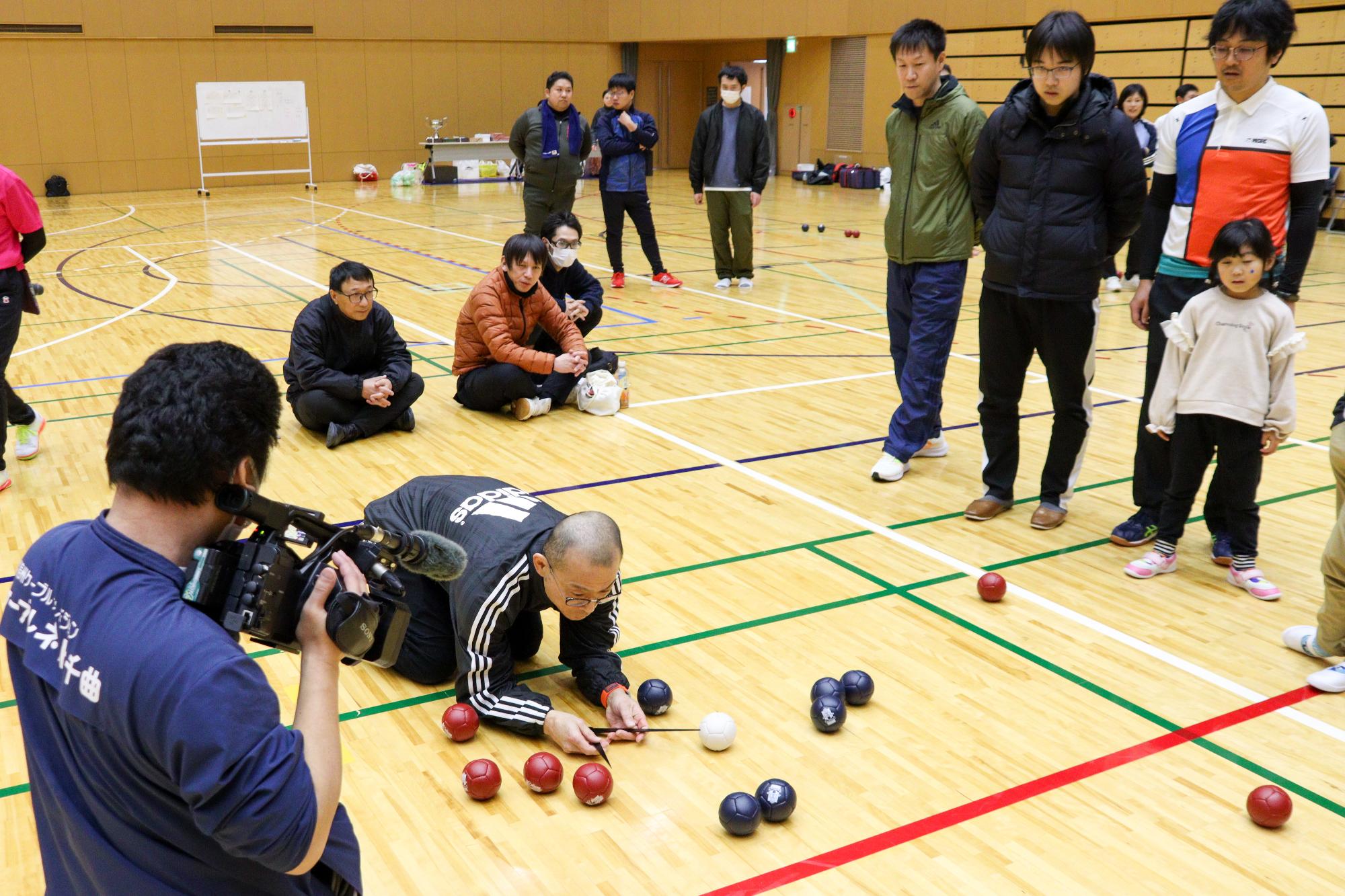 投球が終了し、大勢が見守る中、ジャックボールからの距離を計測する審判