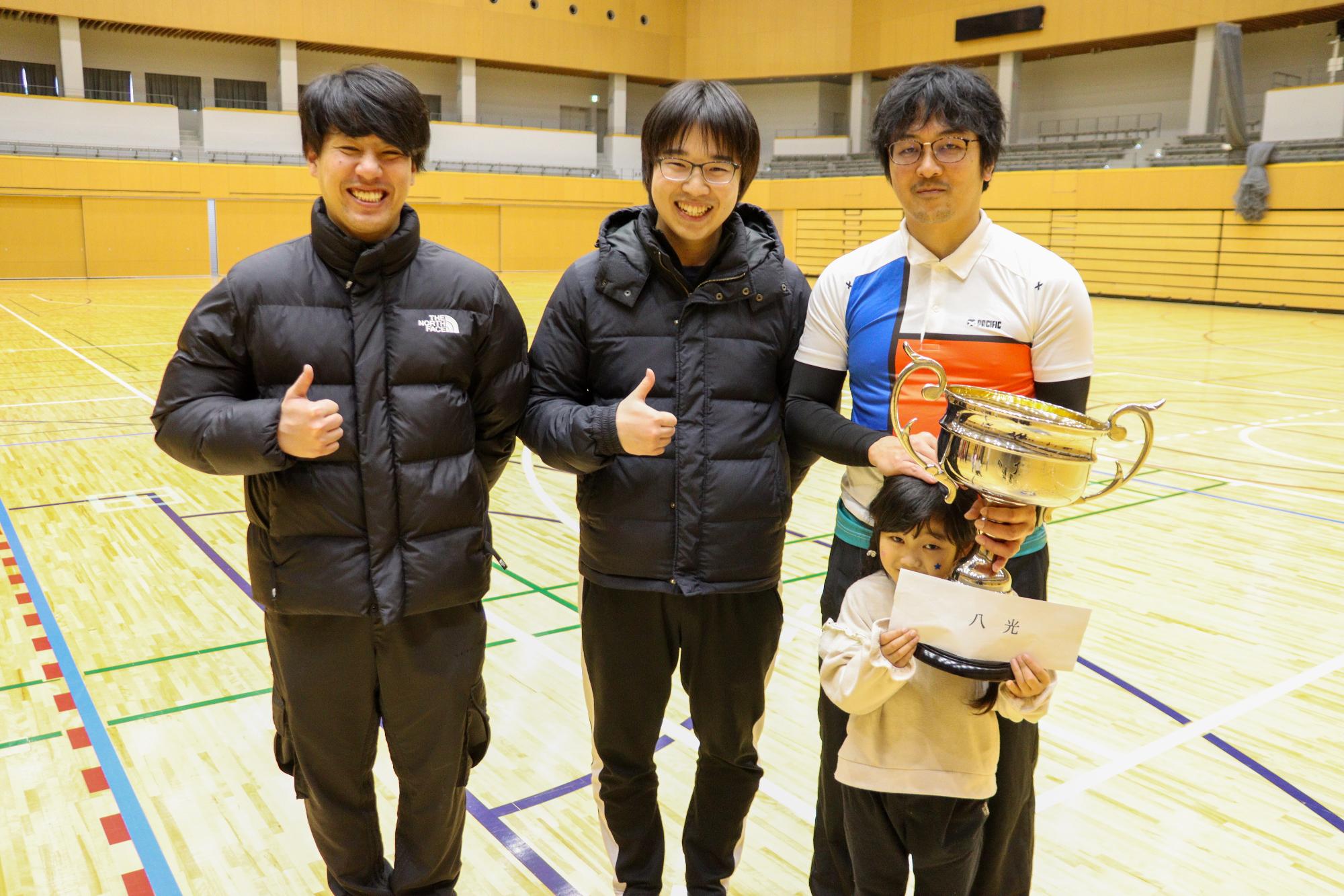 優勝した八光チームの4人が優勝カップなどをもって記念撮影