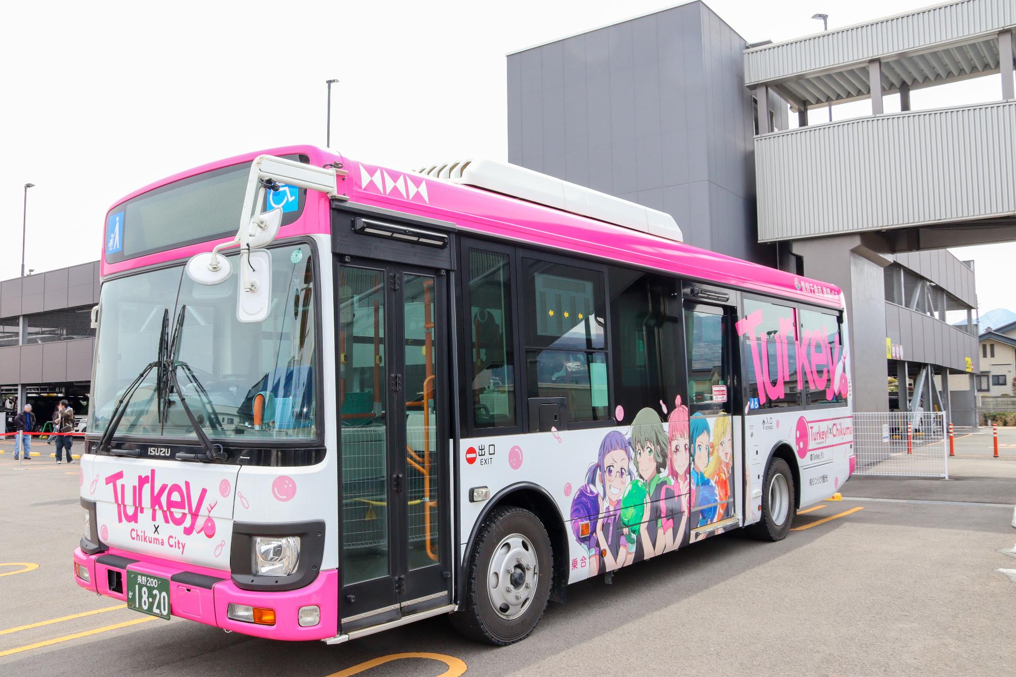 テレビアニメ「Turkey!」の絵柄がラッピングされたバスを左斜め前方から撮影。ボウリング部の女子高生5人がボールを持ってポーズを決めている絵柄がラッピングされているカラフルなバス。