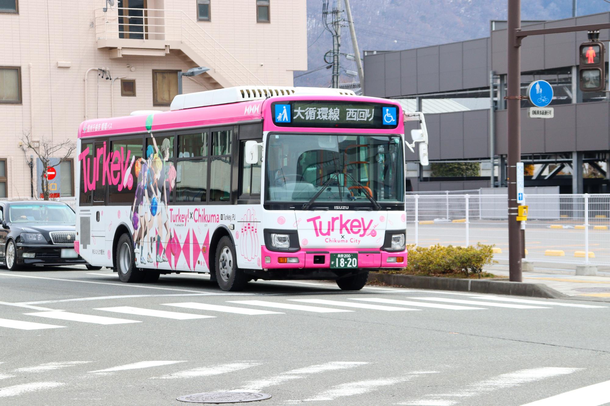 運行を開始し、市役所前交差点を通過するラッピングバスの様子。