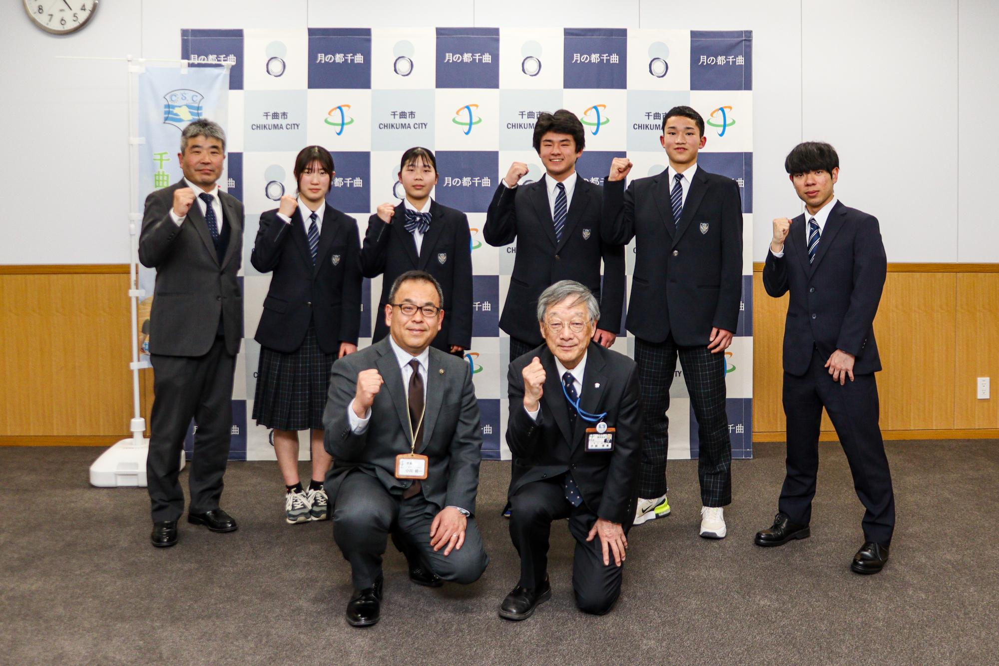 男女8人がガッツポーズをしながら記念撮影
