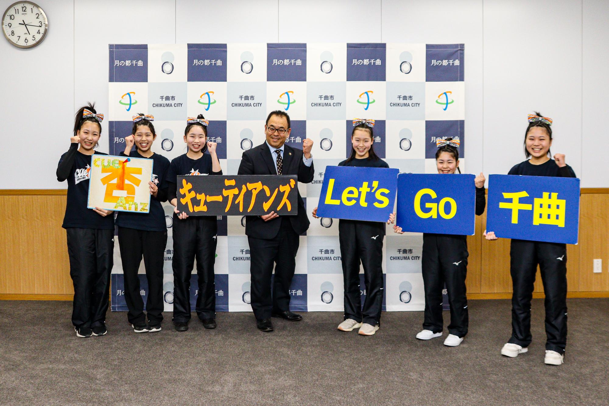 選手6人と市長が杏・キューティアンズ・Let's Go 千曲のボードを持って記念撮影している様子