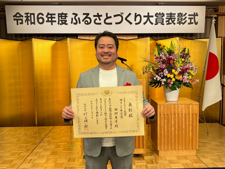 2月10日の授賞式で賞状を受け取り記念撮影をする田村さん