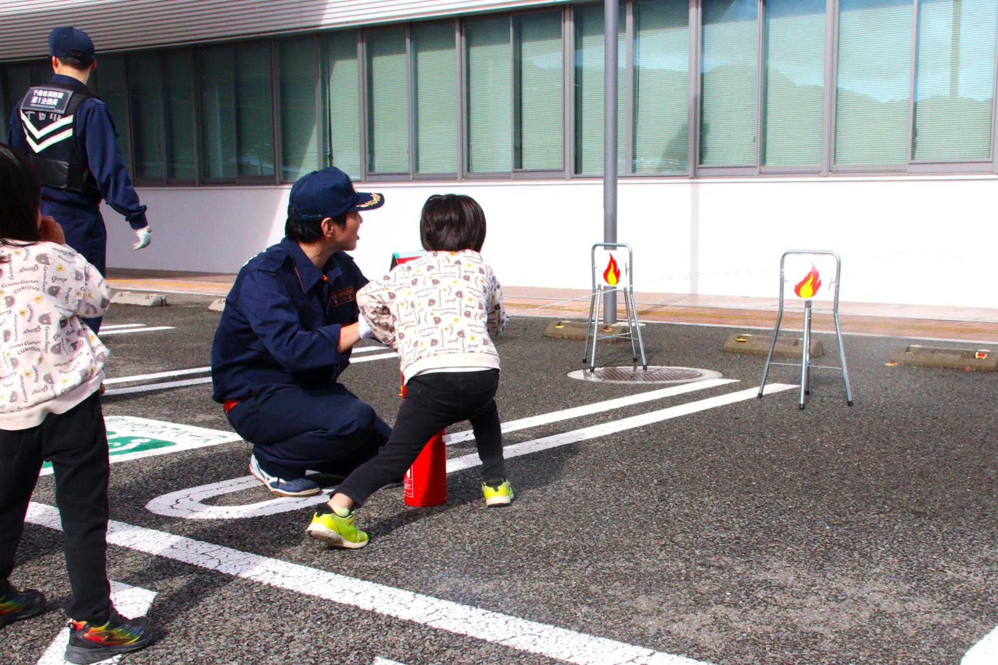 消火器放水体験を行なう子どもと消防団員