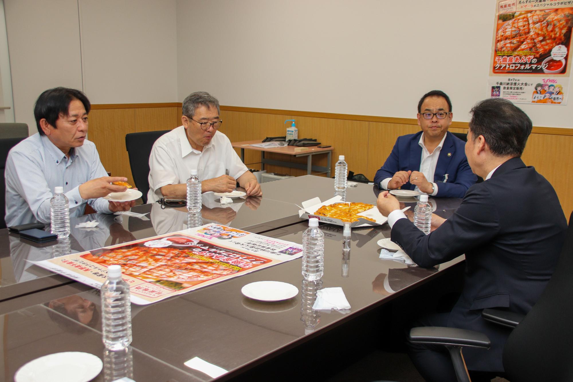 オリジナルピザを食べながらピザの味などについて会話をしている様子