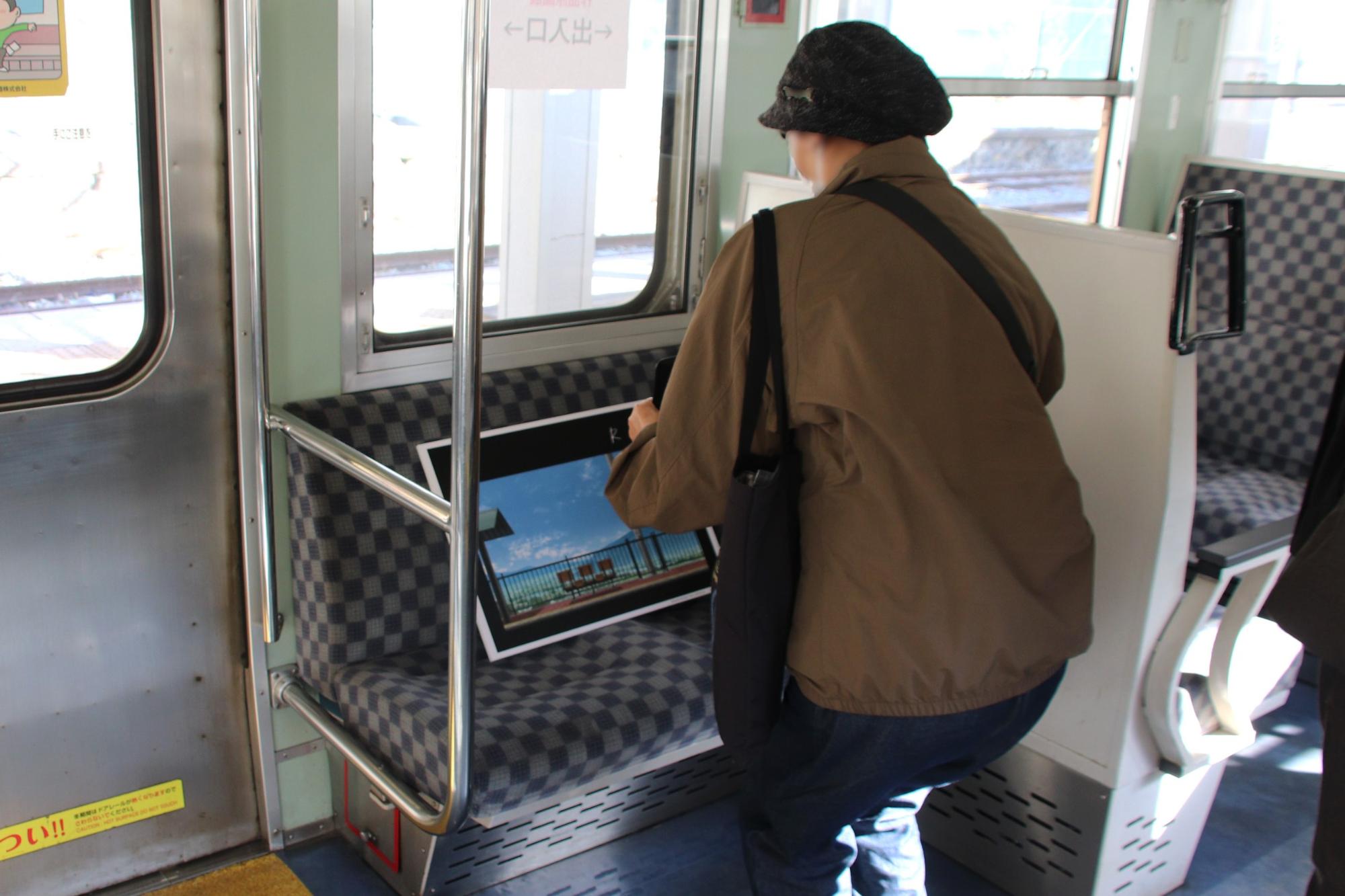 車両内原画展示を見ている来場者