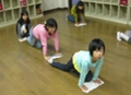 子どもたちが四つん這いになって並び、床にぞうきんをかけている写真