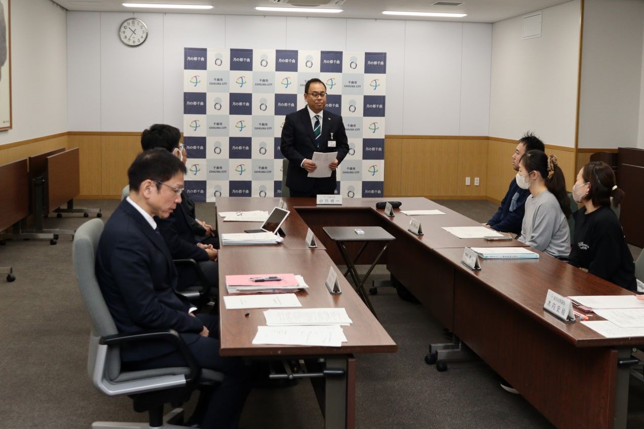 小川市長が机に座っている検討委員に向かって挨拶をしている写真