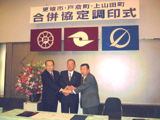 調印式で固く握手を結ぶ市長、町長、知事の写真