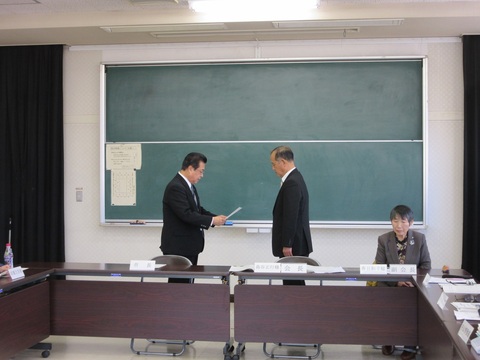 会議室内でスーツ姿の男性二名が向かい合って諮問を取り進める様子を撮影した写真
