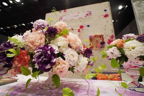 色とりどりの花を使ったフラワーアレンジメント作品がテーブルの上にふたつ並んでいる写真